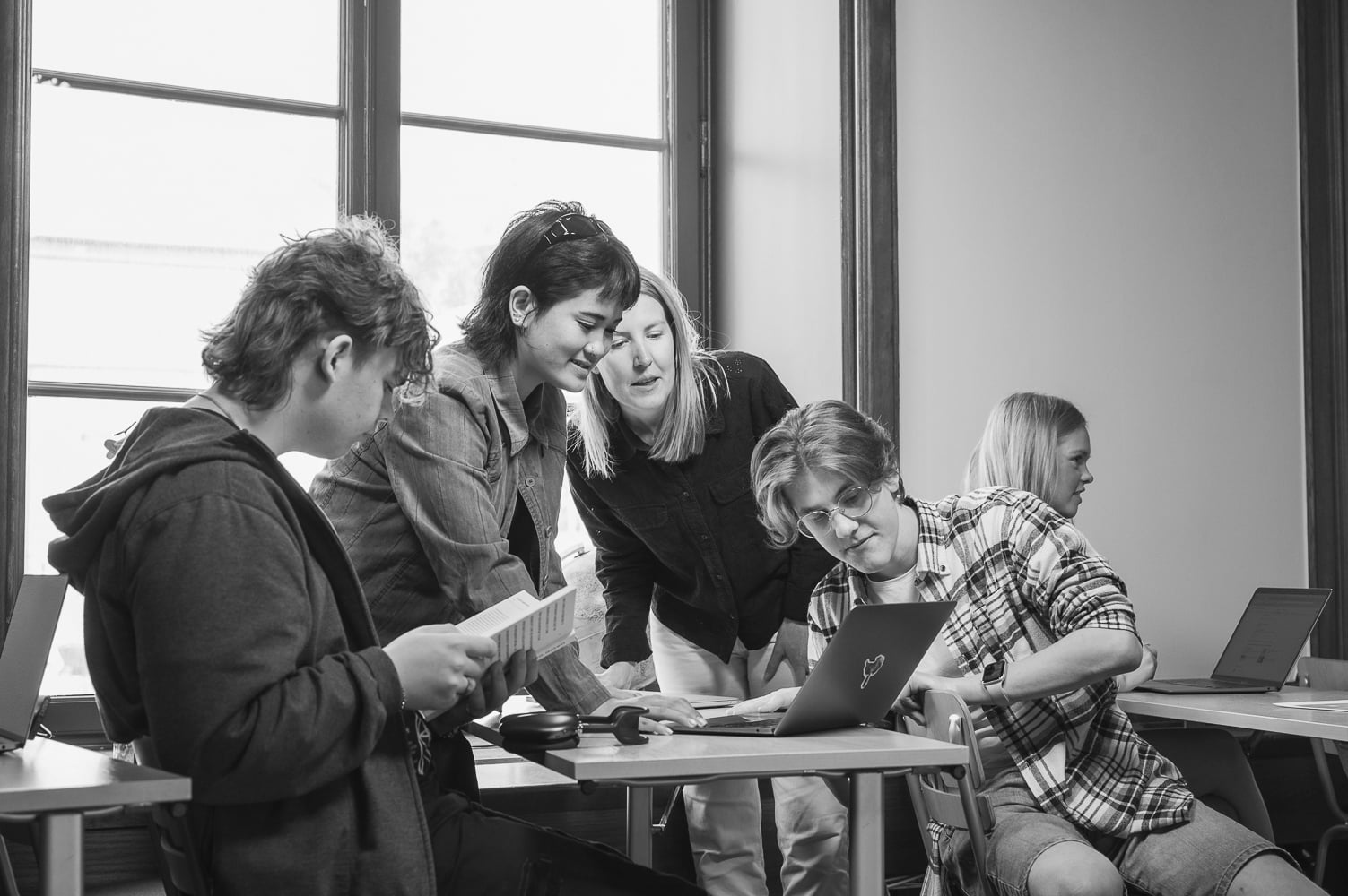 Elever jobbar i grupp i ett klassrum, svartvitt.