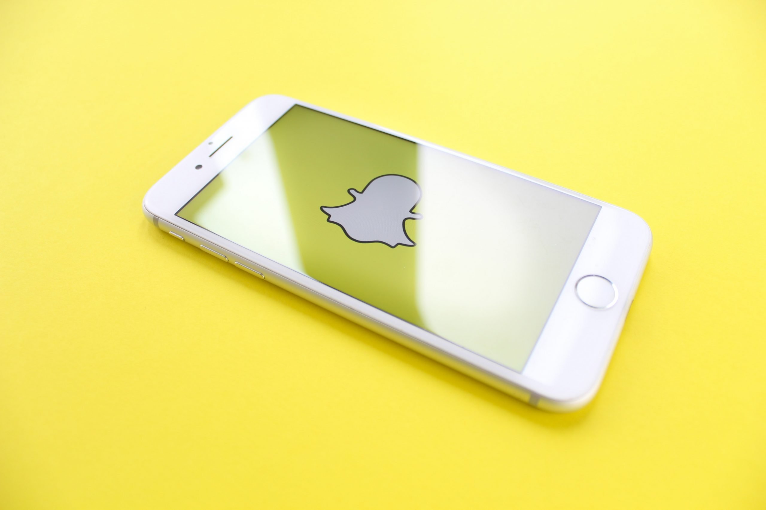 En iphone ligger på en gul yta och visar snapchats logga på skärmen.